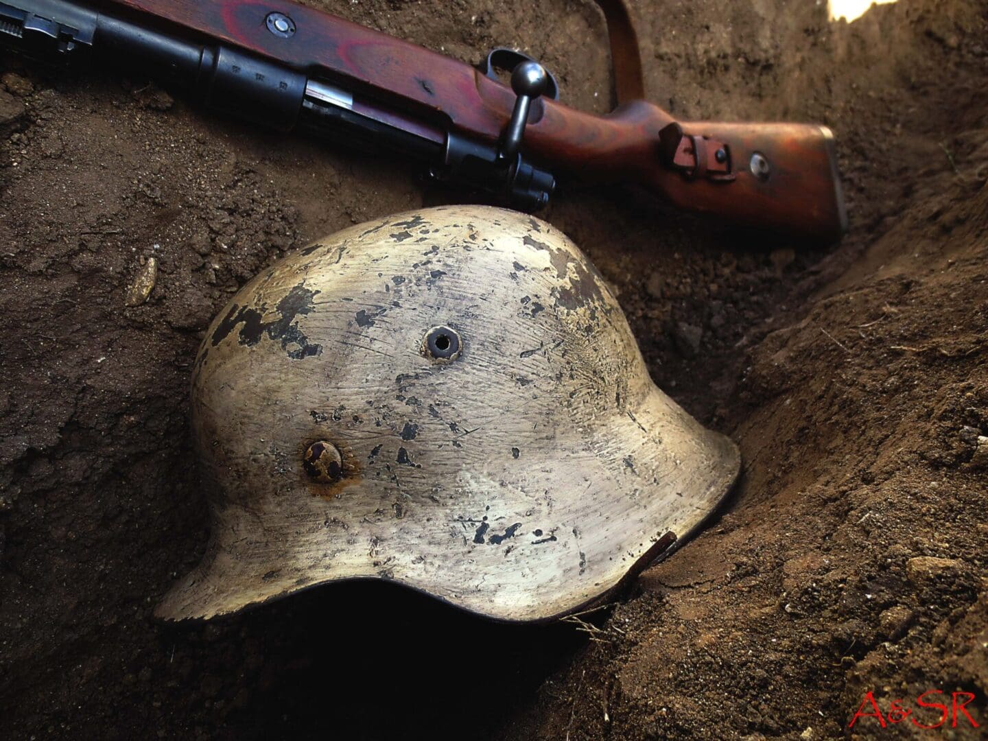 A helmet and rifle lying on the ground.