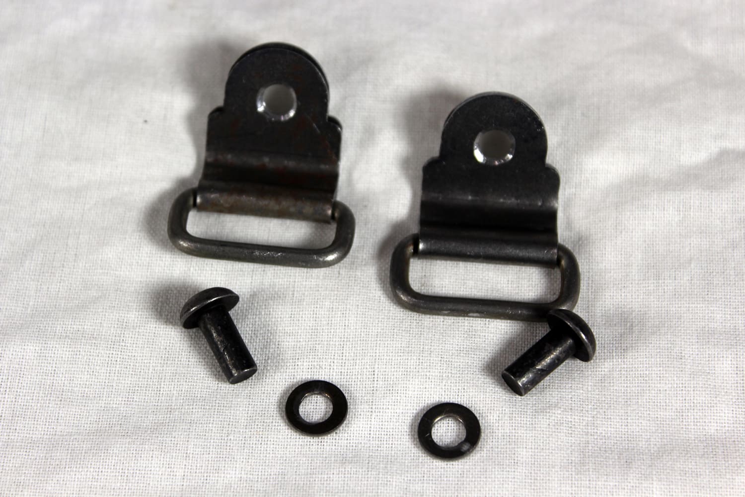 A pair of black metal straps with two small screws and one large screw.